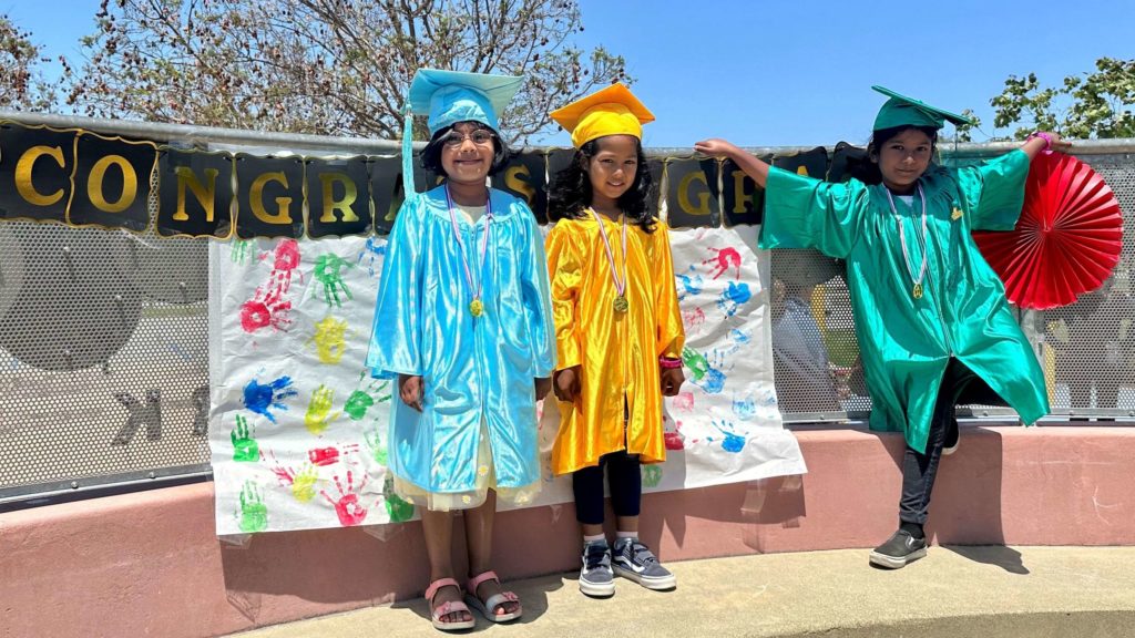 three young students in graduation gowns and caps