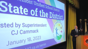 Person at podium in front of State of the District presentation