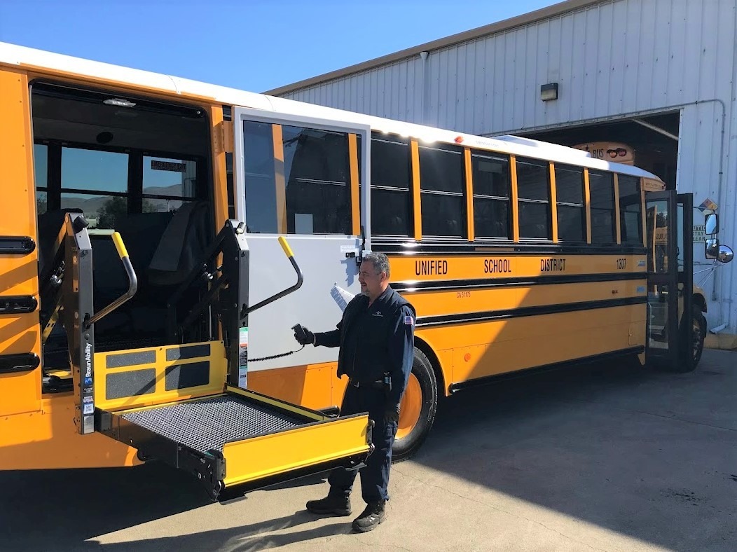 worker operating wheelchair lift on bus