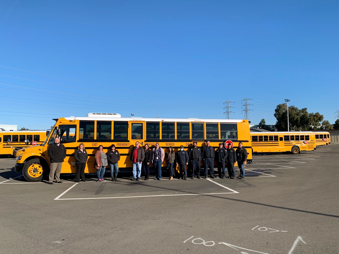 group of employees standing in front of bus