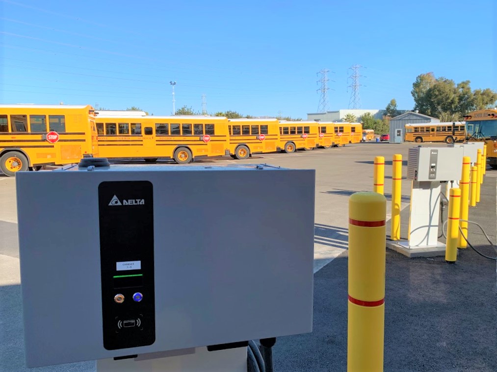 parking lot charging station with row of buses in background