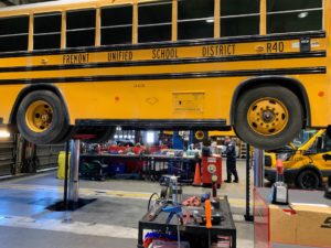 technician under bus lifted for inspection