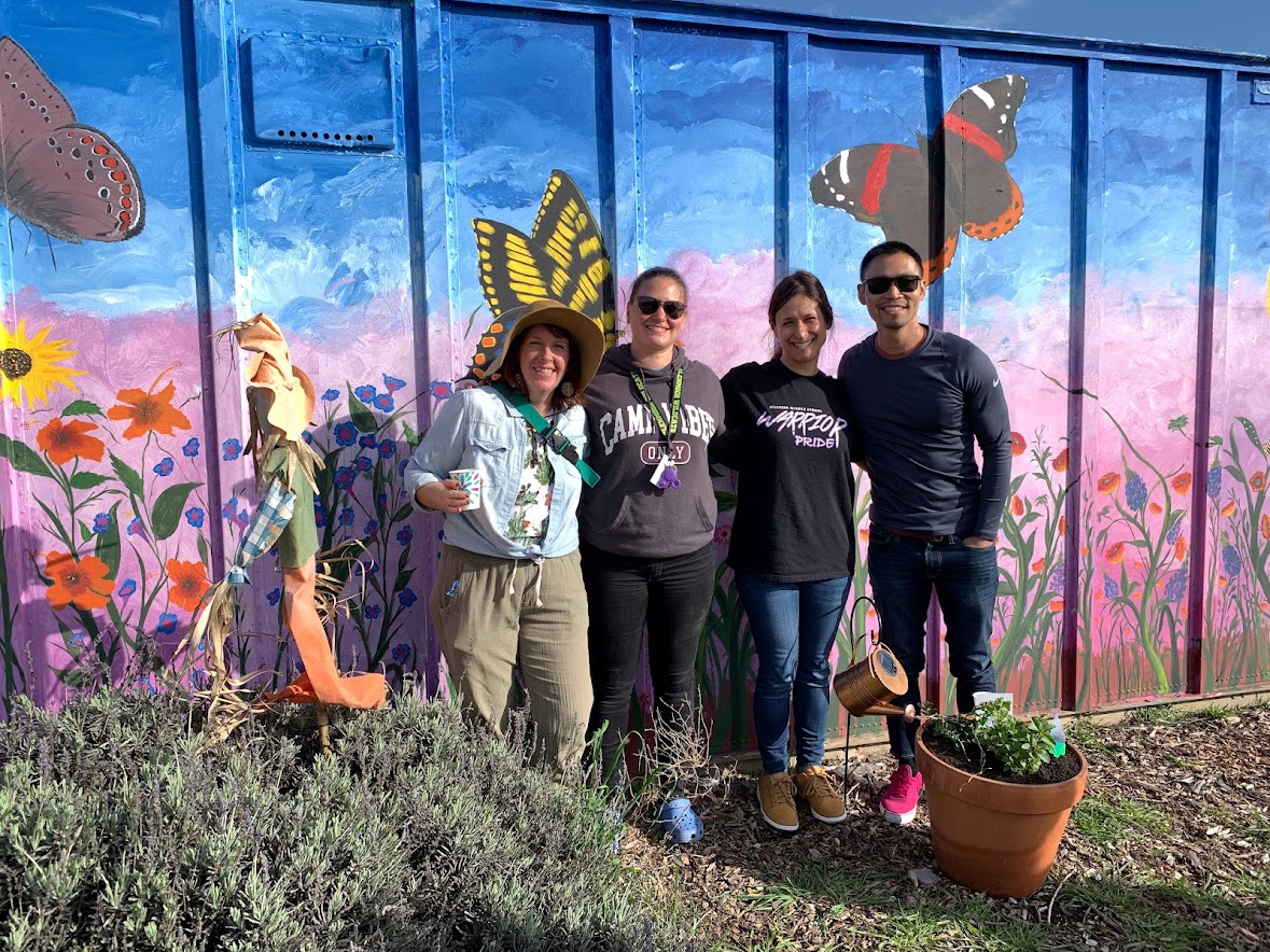people standing in front of butterfly mural in garden